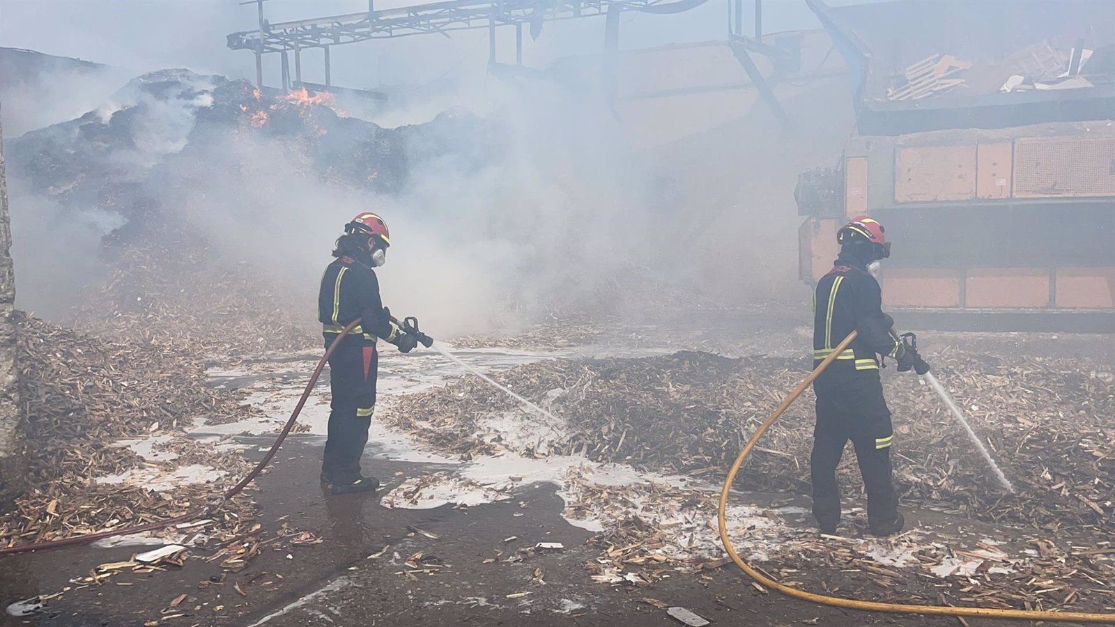 Los bomberos trabajan en la extinción de un incendio de material para reciclaje almacenado en Alcalá