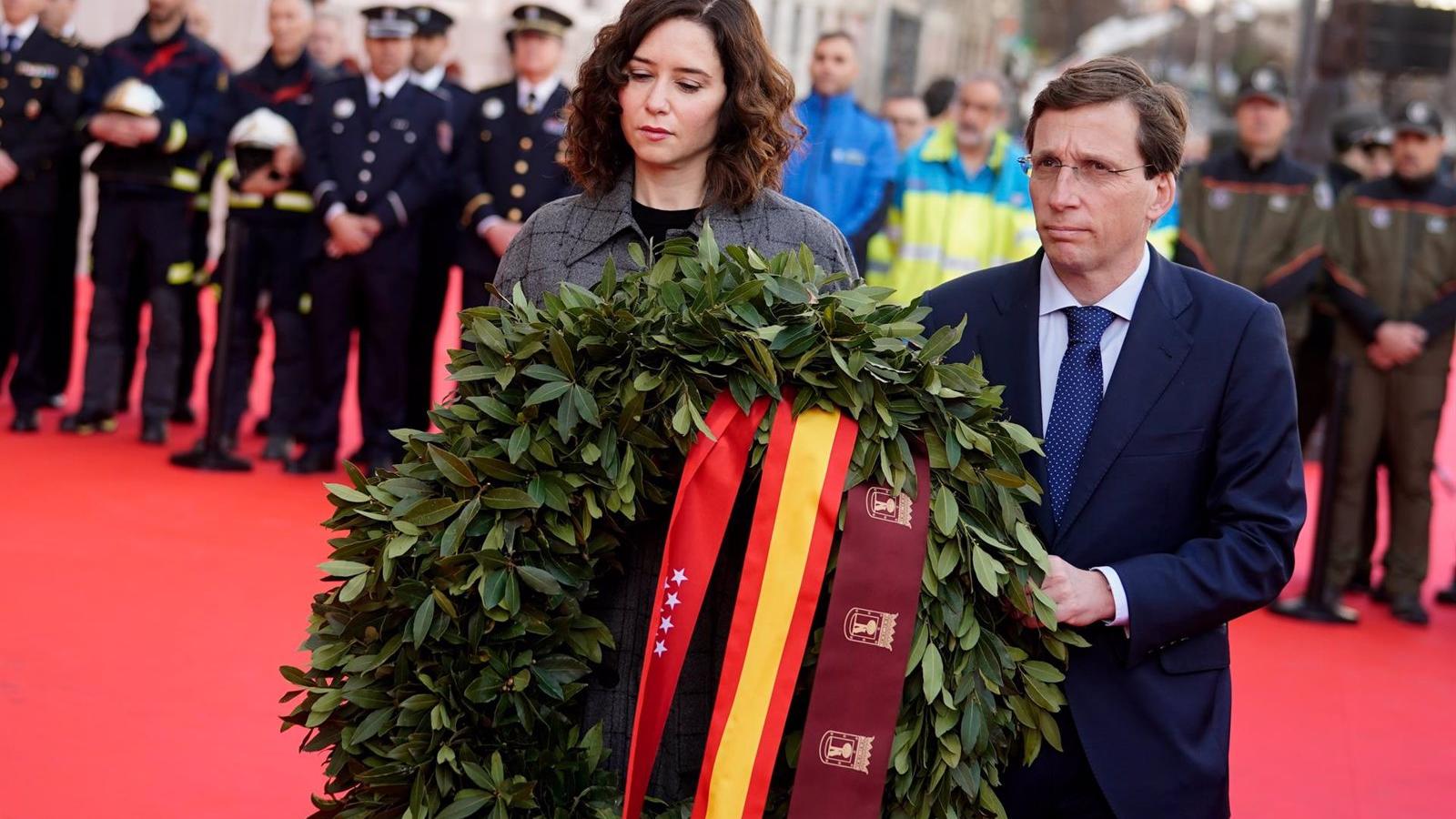 Díaz Ayuso y Martínez-Almeida recuerdan a las víctimas con una corona de laurel mientras tañen las campanas de las iglesias de Madrid